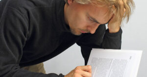 man intensely studying pages of a document