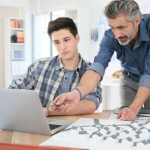 Instrcutor with student showing something on laptop